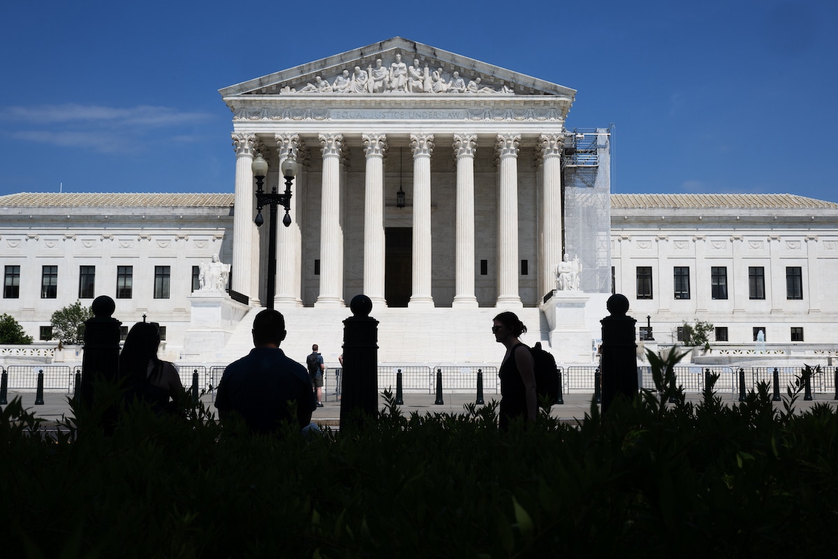 Several shadowy figures of people stand outside the U.S. Supreme Court in Washington, DC